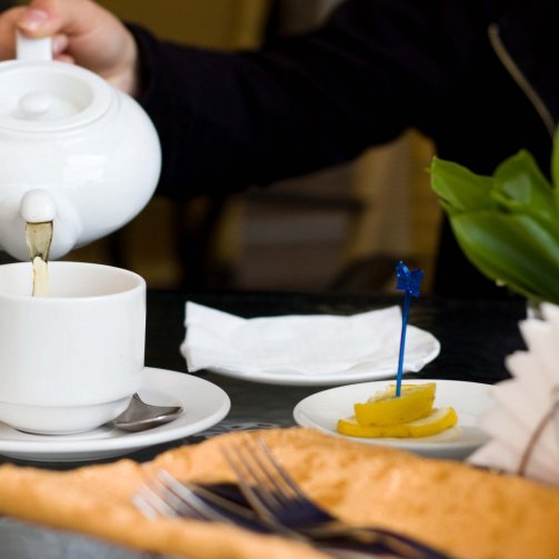 white cup and teapot with green tea in cafe